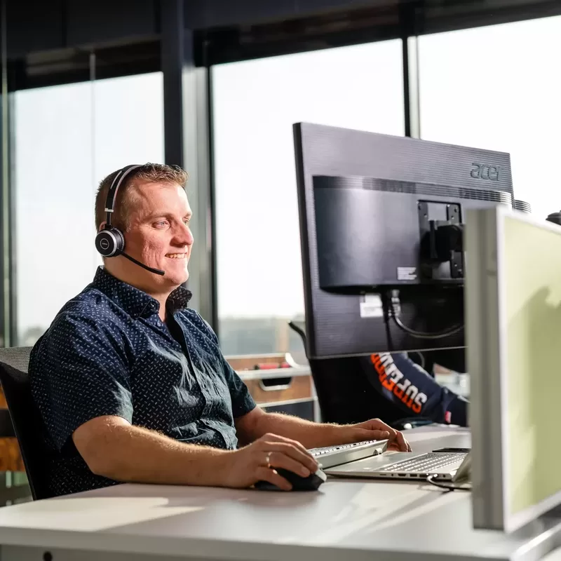 Een medewerker belt met een headset via hosted Voip of Microsoft Teams bellen